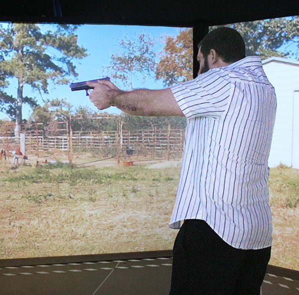 Man aiming gun in front of simulated screens