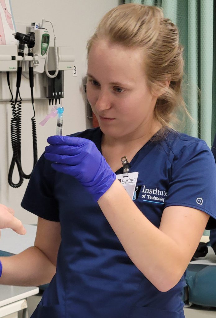 Woman in scrubs examining a syringe